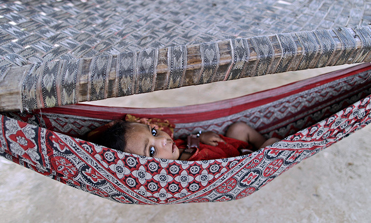 24 hours in pictures: Pakistani child lays in a hammock attached to bed 