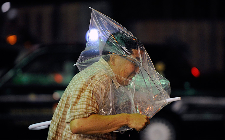 24 hours in pictures: A man struggles to control his umbrella against strong winds in Tokyo