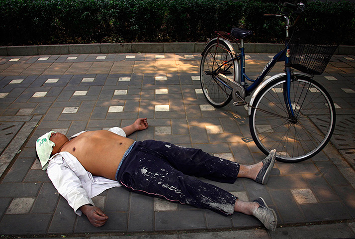 24 hours in pictures: A man sleeps next to his bicycle in central Beijing
