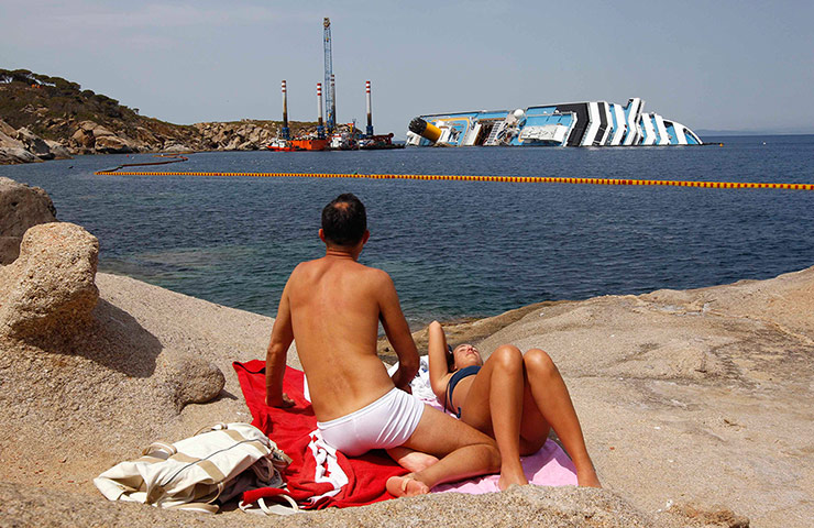 Picture desk live: A couple sunbathe in front of Costa Concordia 