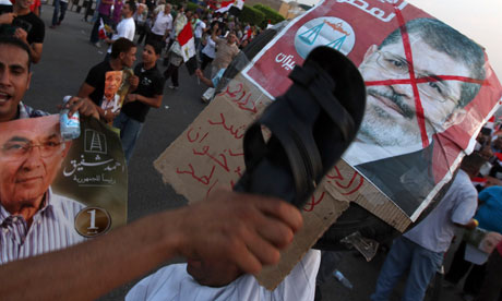 Supporter of presidential candidate Ahmed Shafiq hits defaced poster of Mohammed Morsi 