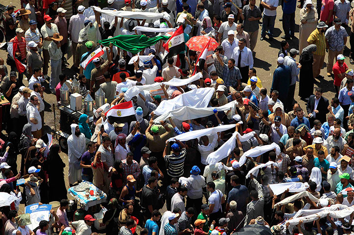 Egypt elections: Supporters of Mohamed Morsi carry sheets symbolising coffins