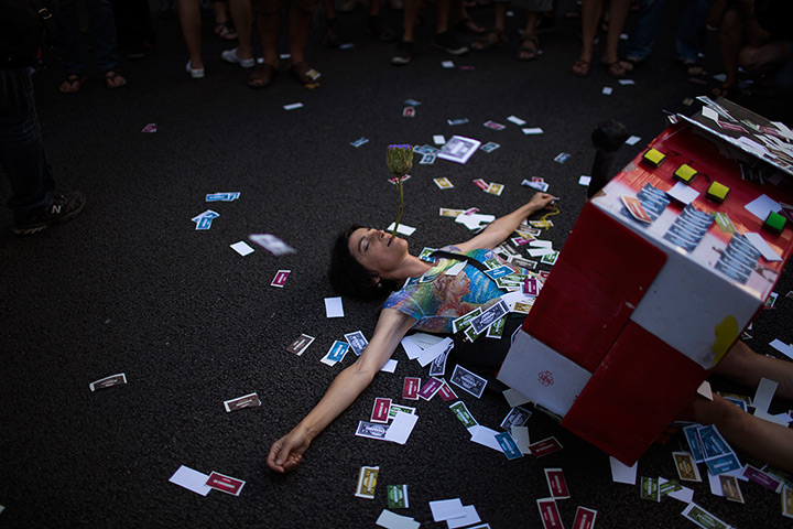 24 hours in pictures: A protester lays on the ground covered by fake notes, Spain