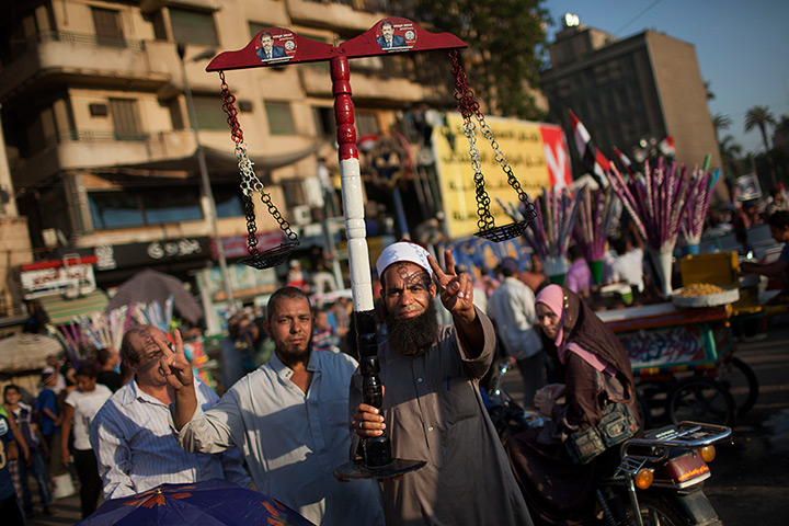 24 hours in pictures: A man flashes the victory sign as he carries a scale, Cairo