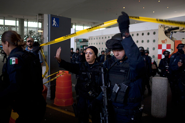 24 hours in pictures: Federal police officers lift a strip of crime scene barrier tape, Mexico
