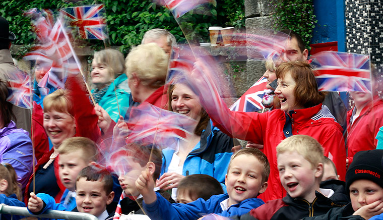 Queen: Members of the public wave their Union Jack flags as they wait the Queen