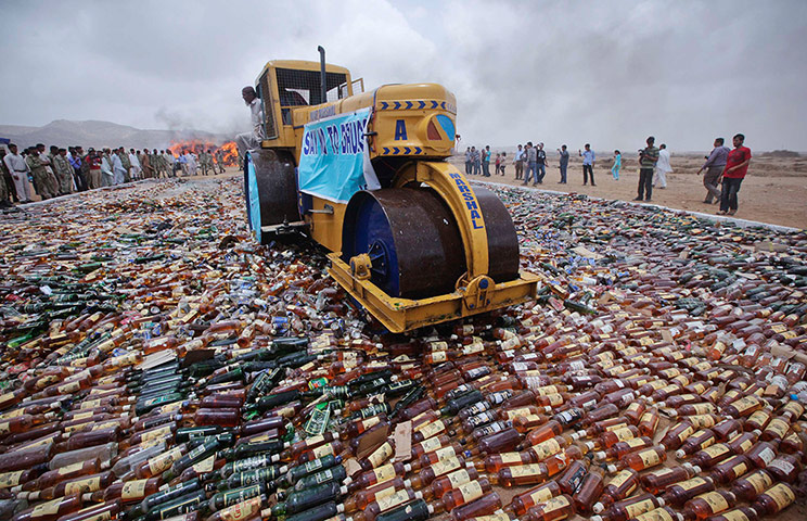 Picture Desk Live: A steam roller moves through a pile of confiscated liquor bottles