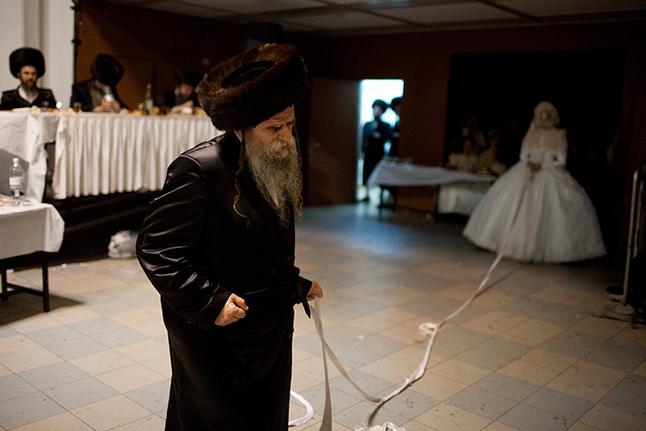 24 hours in pictures: Jewish Bride holds a strip of cloth attached to the father of the groom