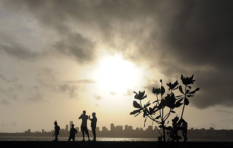 24 hours in pictures: Indians stroll near the seafront as dark clouds gather over city skyline