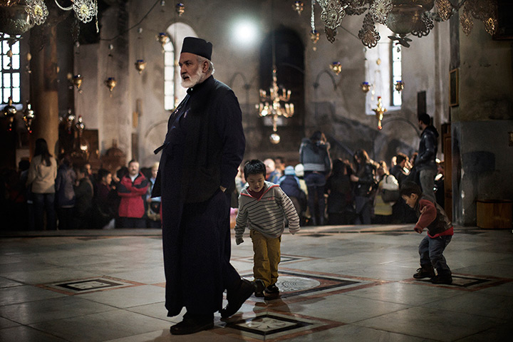24 hours in pictures: Orthodox priest walks past children playing inside Church of the Nativity