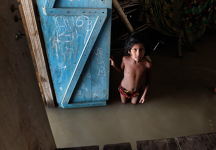 24 hours in pictures: A flood affected child inside her submerged house