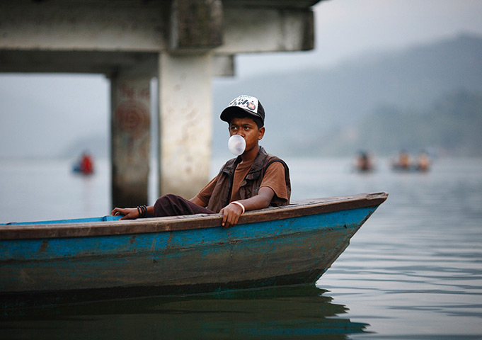 24 hours in pictures: A boy resting in a boat blows a bubble on Phewa Lake in Pokhara valley
