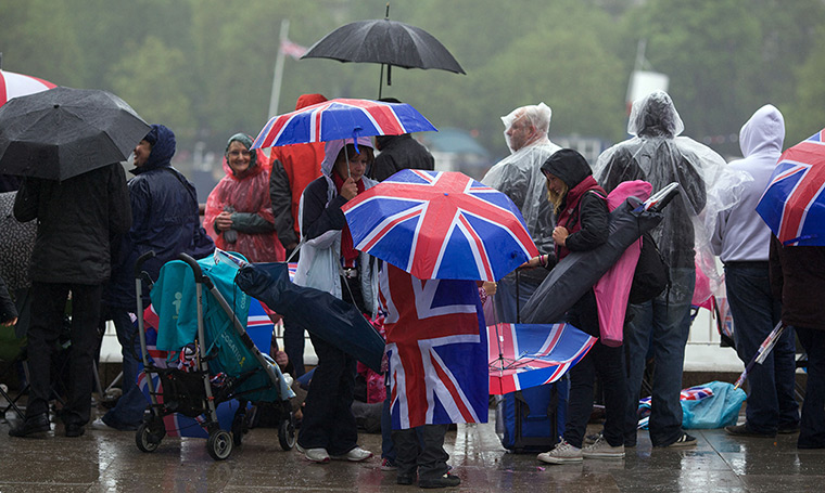 Jubilee pageant: Revellers hide from rain under Union Jack umbrellas