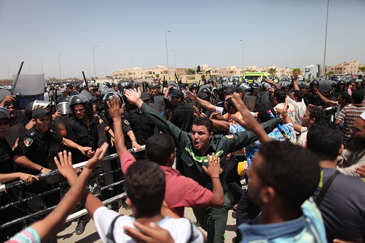Mubarak trial: Egyptian riot policemen stand guard as protestors react outside a court 