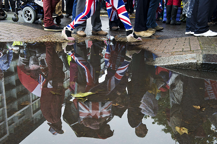 Jubilee pageant update: A woman wearing Union Jack leggins is reflected in a puddle Battersea Park
