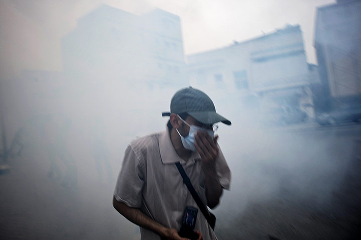24 hours: Belad al-Qadeem, Bahrain: A Shiite Muslim covers his face from the tear gas