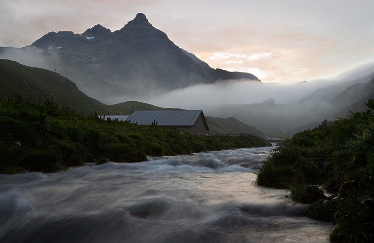 24 Hours: Mist hangs between the mountains at dawn near the Julier pass in Bivio