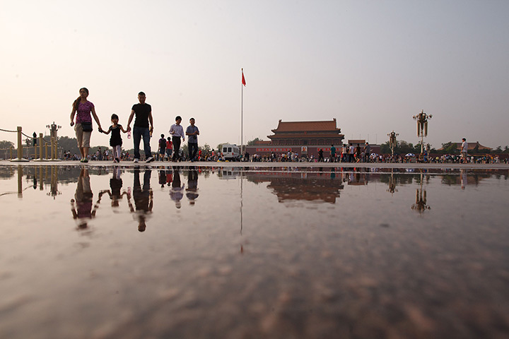 24 hours: Beijing, China: People are reflected in a puddle in Tiananmen Square 