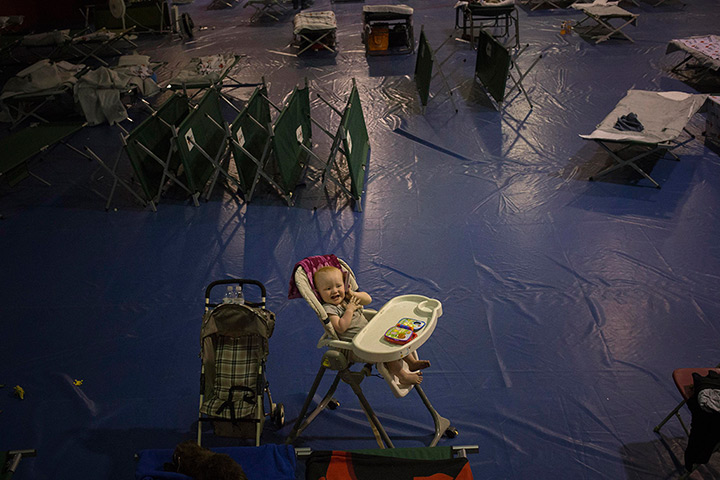 24 hours in pictures: An evacuee baby plays in his high chair at a Red Cross evacuation centre