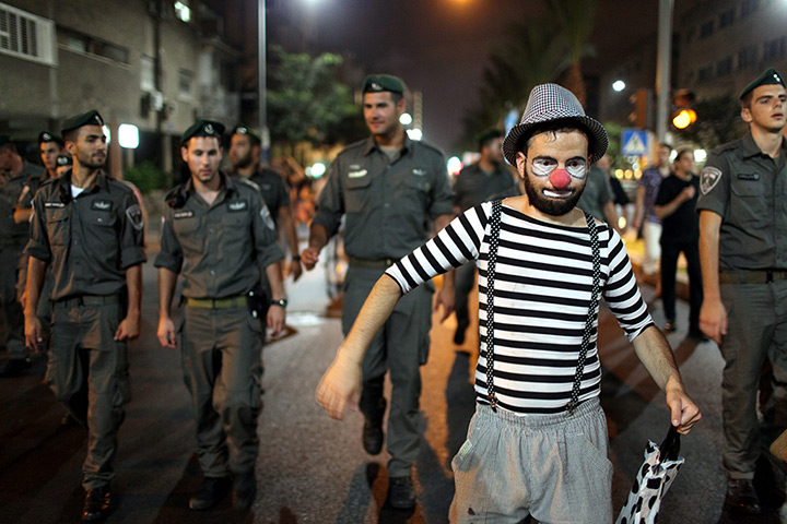 24 hours in pictures: Israeli protester dressed as clown walk next to a Israeli  border police