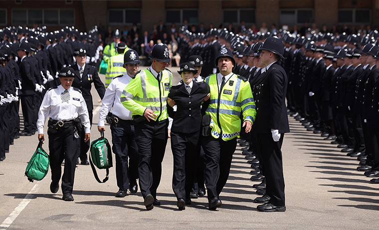 24 hours in pictures: A police officer is helped by colleagues as she becomes faint