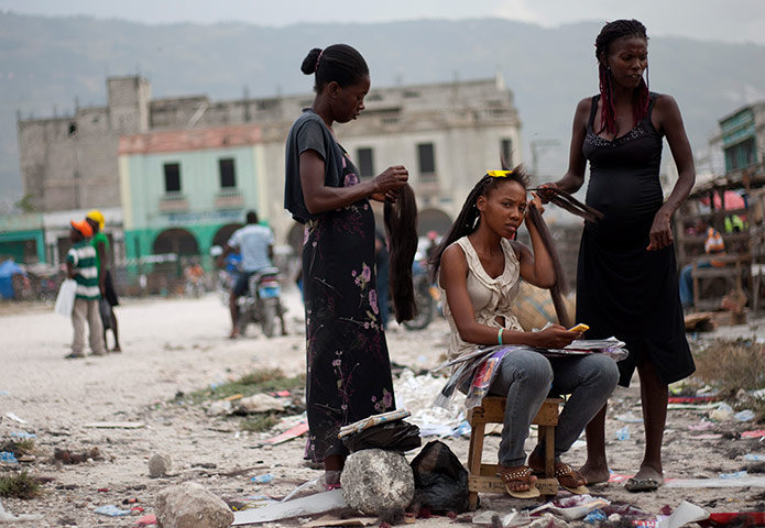 Picture desk live: A customer has her hair done by hairdressers on a street in Haiti