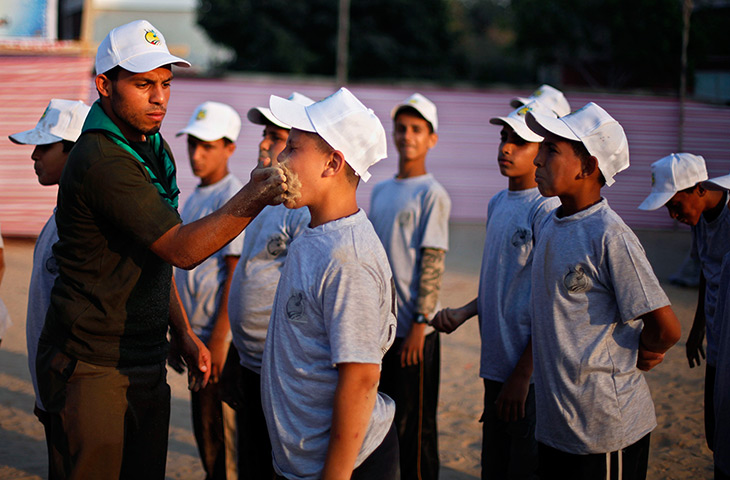 24 hours in pictures: A trainer puts sand inside the mouth of a Palestinian child during training