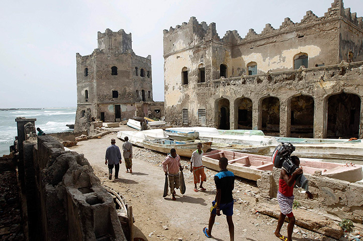 Somalia Goran Tomasevic: A man carrying fish walk past buildings destroyed during the warMogadishu