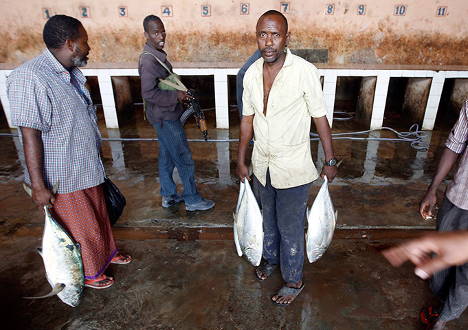 Somalia Goran Tomasevic: A man carries fish in a market in Mogadishu