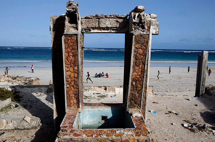 Somalia Goran Tomasevic: Men sit on a beach in front of a destroyed building in Mogadishu