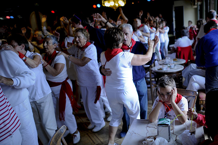 24 hours: Pamplona, Spain: A bored child sits at a table while people dance