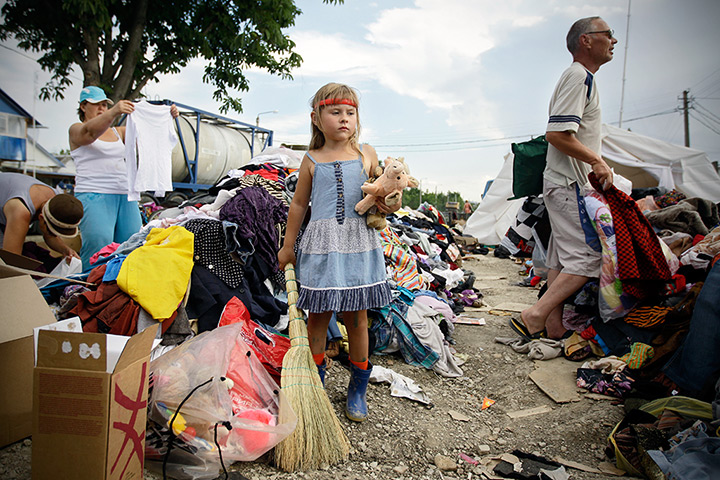 24 hours: Krymsk, Russia: A girl stands with toys and broom at a distribution centre