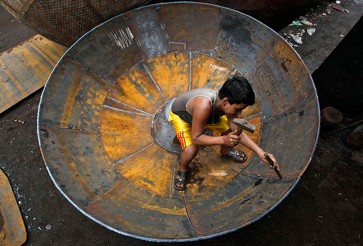 24 hours: Kolkata, India: A boy checks the joints of a giant utensil