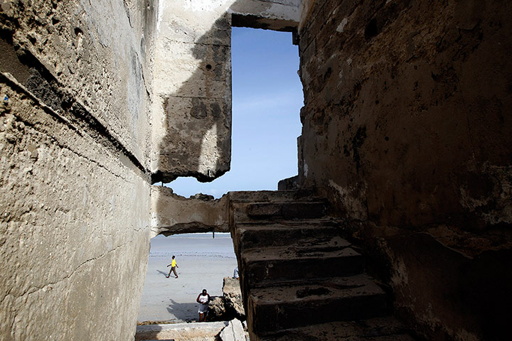 Mogadishu: Men walk on a beach in front of a building destroyed 