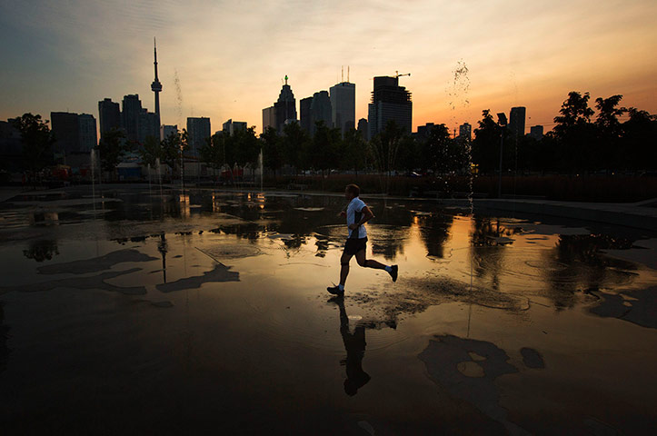 24 Hours: Toronto, Canada: A man jogs through water fountains