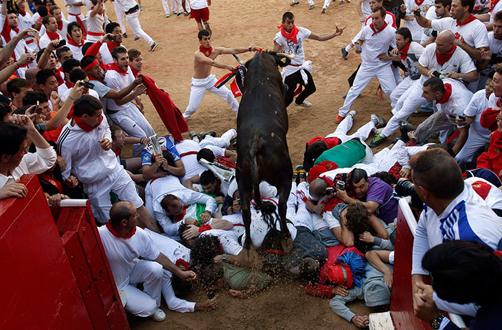 24 Hours: Pamplona, Spain: A wild cow jumps over revellers during festivities