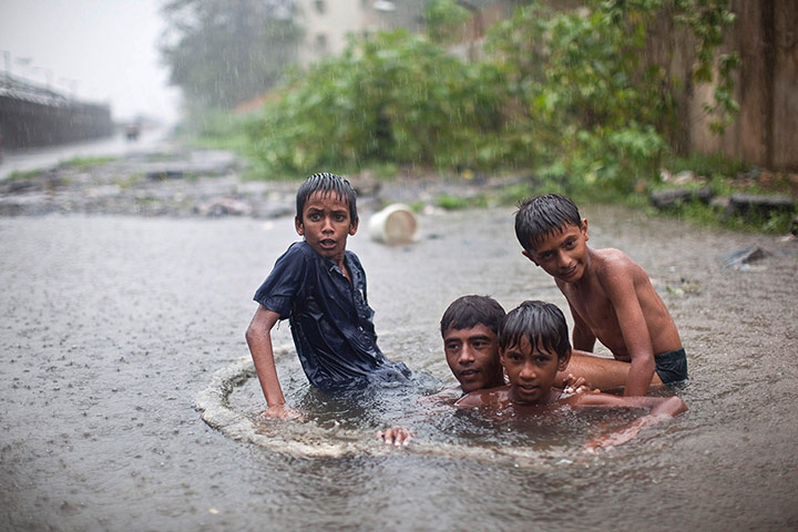 A Longer View - Flooding: Boys play inside a drain as it rains in Mumbai