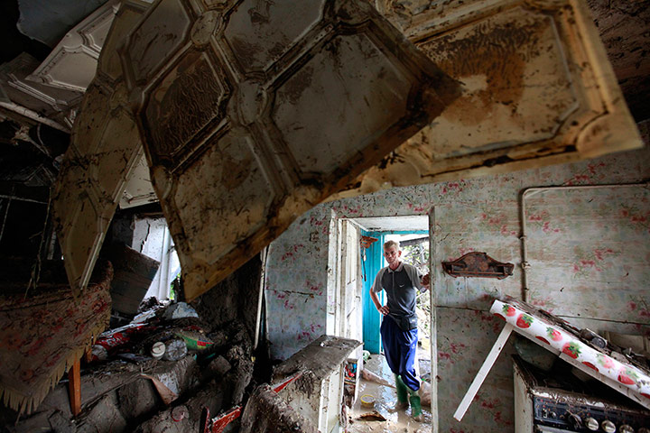 A Longer View - Flooding: A local resident looks at the debris of a house damage