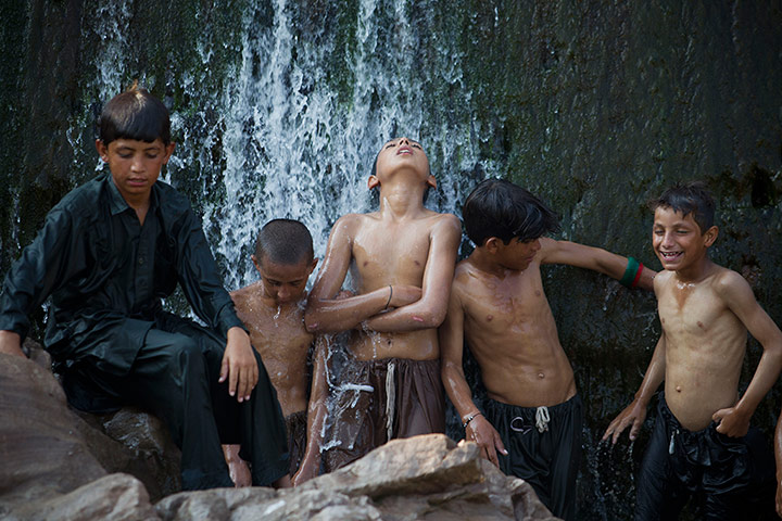 Picture Desk Live: Pakistani children enjoy cool water from a waterfall after a monsoon rains