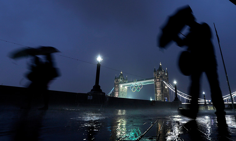 24 hours: London, England: Pedestrians walk past Tower Bridge with the Olympic rings 