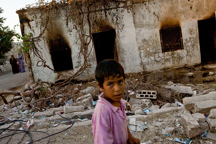 Tremseh, Syria: A boy walks past a burnt house in the village