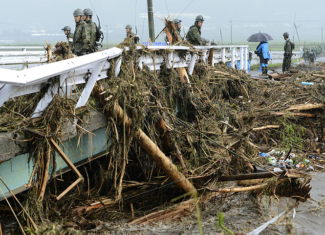 Floods in Japan: Ground Self-Defence Force personnel look at trees carried by floodwaters