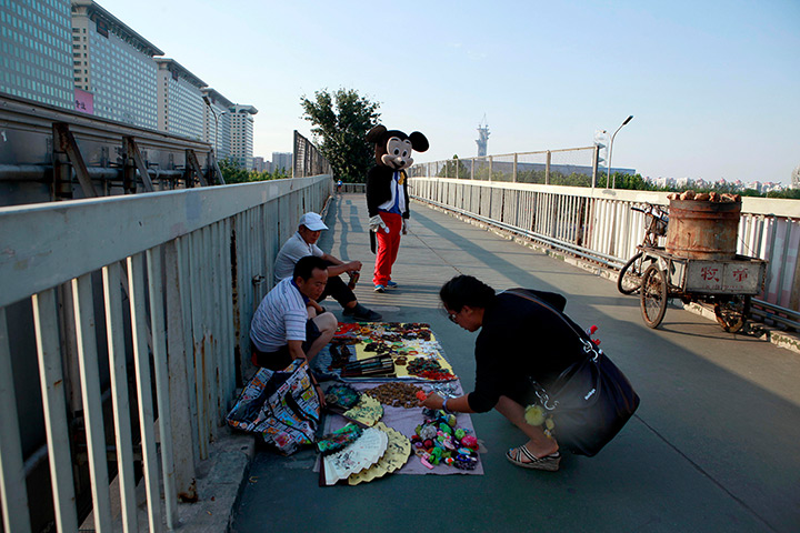 24 hours: Beijing, China: A man wears a Mickey Mouse costume to pose for photos