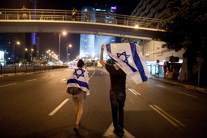 Tel Aviv protests: Demonstrators wave their national flag as they march through the streets