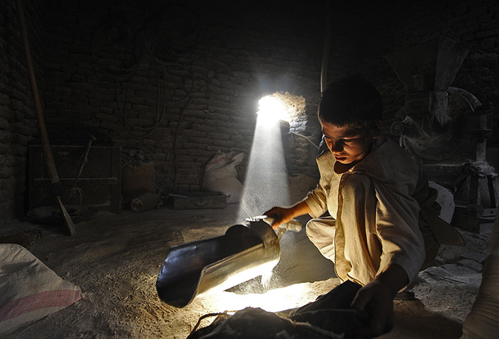 24 hours: Nahr-e Shahi, Afghanistan: A young Afghan labourer grinds wheat at a mill