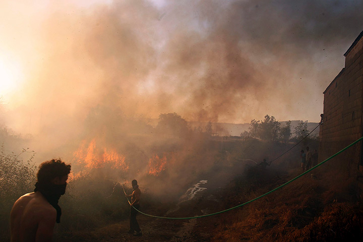 24 hours: Molinaseca, Spain: A man uses a hose to fight a fire 