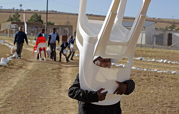 24 hours: Qunu, South Africa: A child carries chairs at the No-Moscow school