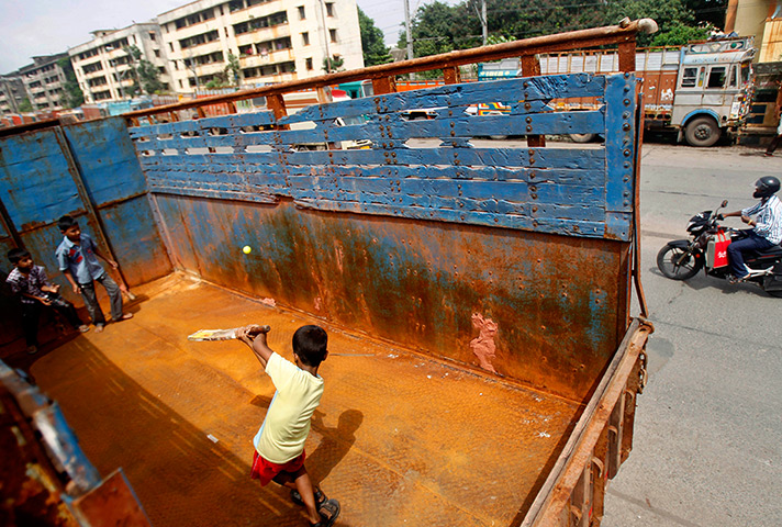 24 hours: Mumbai, India: Children play cricket in the back of a parked truck 