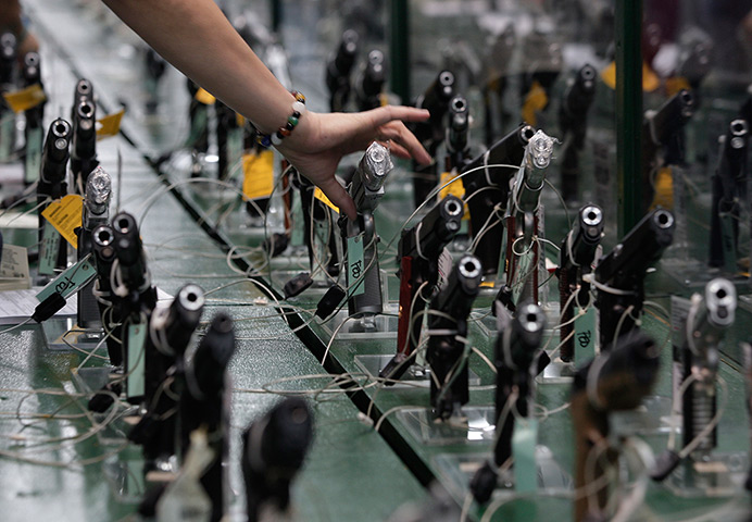  24 hours: Mandaluyong, Philippines: A sales clerk arranges pistols at a gun show