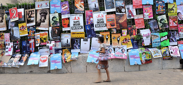 Avignon theatre festival: A man walks past a wall pasted with fly posters